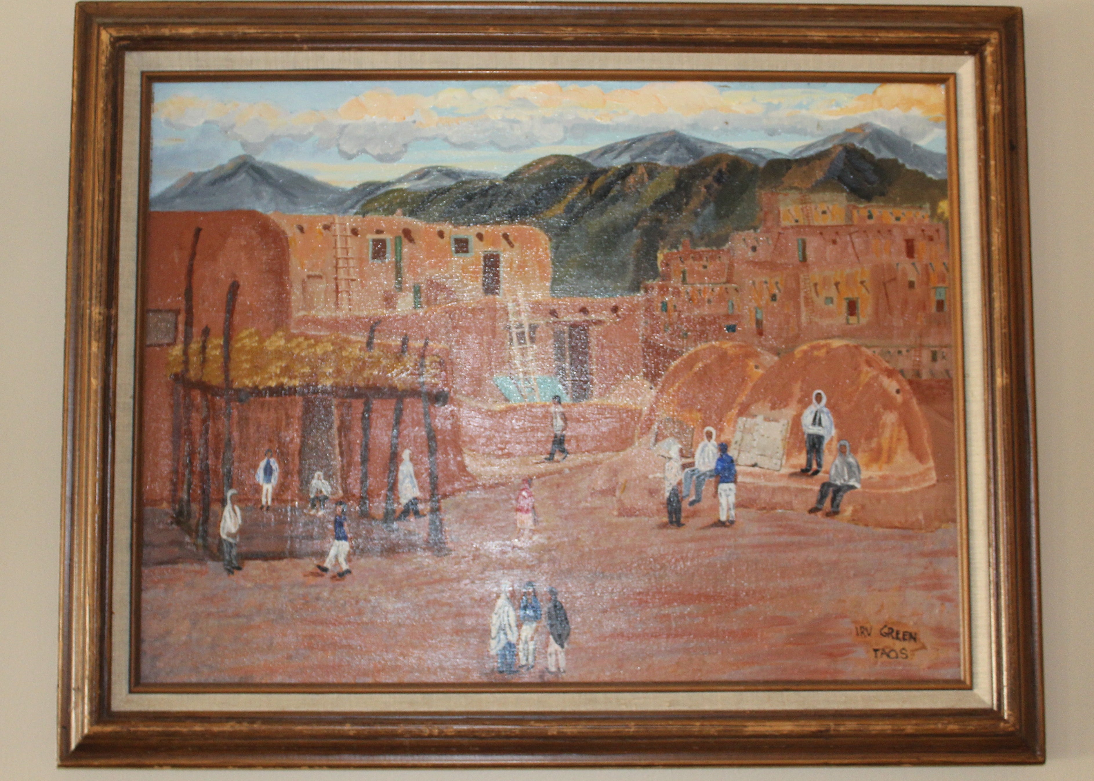 Framed painting of a village scene with mountains 